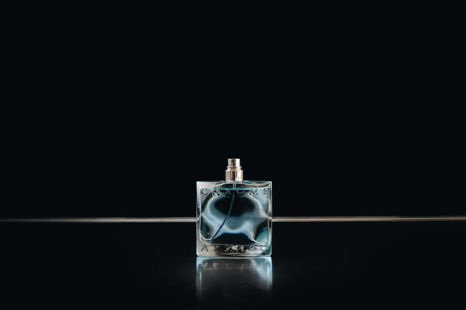 Square glass flacon on a glossy black surface