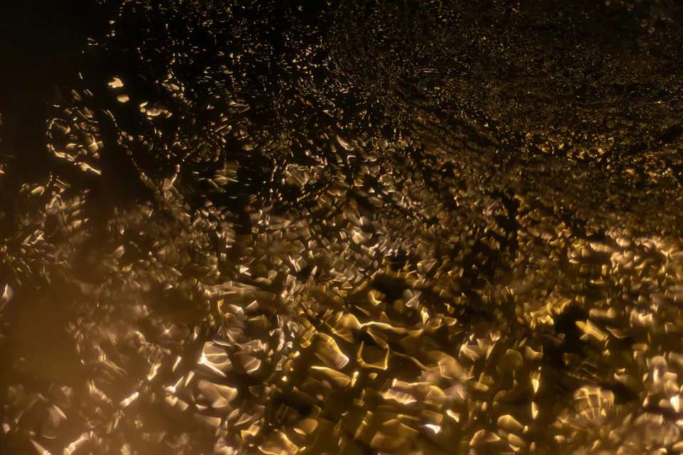 Golden liquid surface rippling in low light