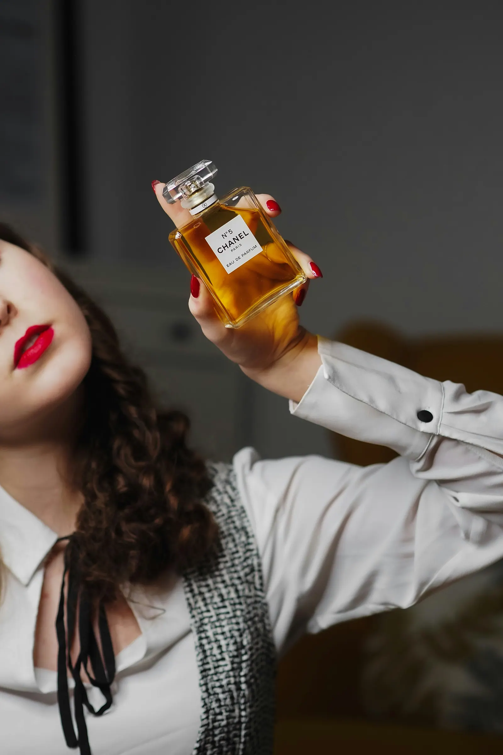Portrait of a woman holding an amber flacon, dark interior