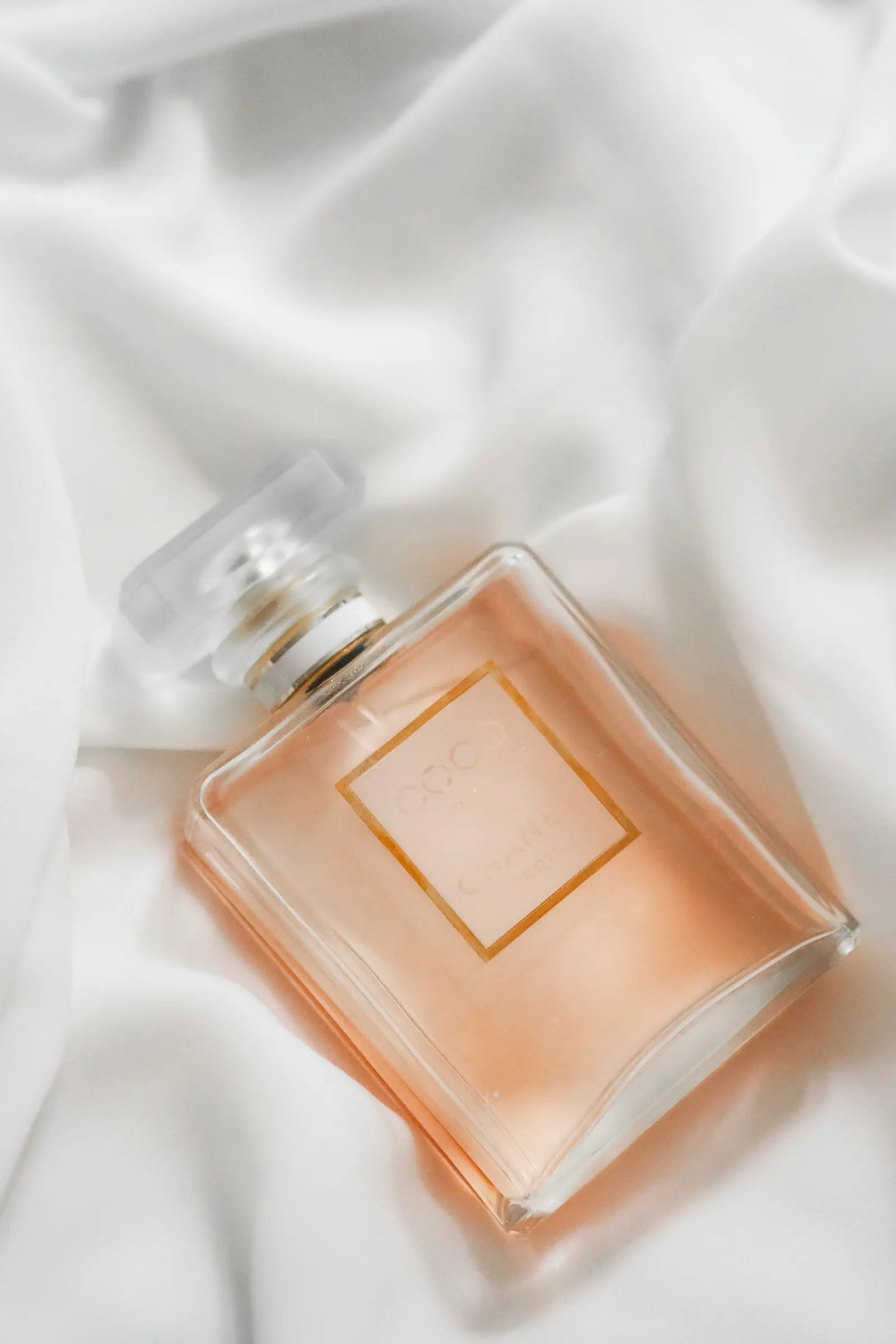 Peach-toned flacon lying on folds of white silk